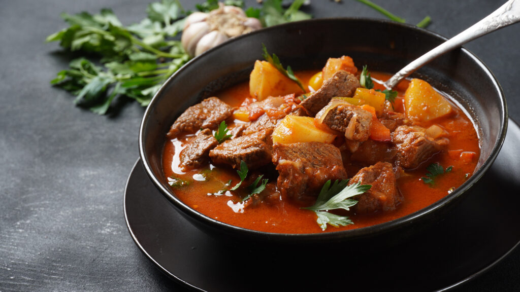 Beef goulash, soup and a stew, made of beef chuck steak, potatoes and plenty of paprika. Hungarian traditional meal.